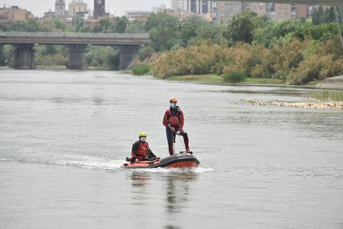 Bomberos de Zaragoza buscan en barca al niño desaparecido en el río Ebro, en Zaragoza.