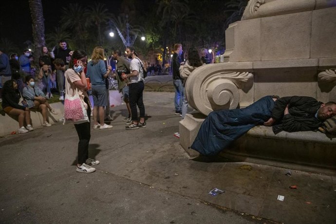 Varias personas en ambiente festivo, frente a una persona sin hogar, en una céntrica calle de Barcelona durante la primera noche sin el estado de alarma, a 9 de mayo de 2021, en Barcelona, Catalunya (España). El estado de alarma que el Gobierno decretó 