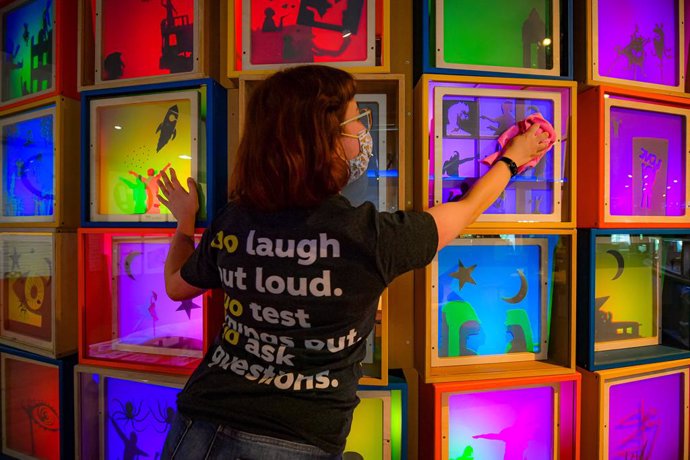 10 May 2021, United Kingdom, Bristol: A woman dusts and cleans backlit colourful light boxes at the science and creative venue, We The Curious, as staff and technicians clean and prepare the Bristol attraction ready for the public ahead of further easin