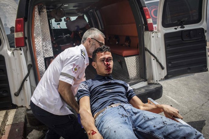 10 May 2021, Israel, Jerusalem: A Palestinian paramedic transports an injured protester during the clashes between Israeli security forces and protesters at Lions Gate in Al Aqsa Mosque compound in Jerusalem's Old City. The Red Crescent organization rep