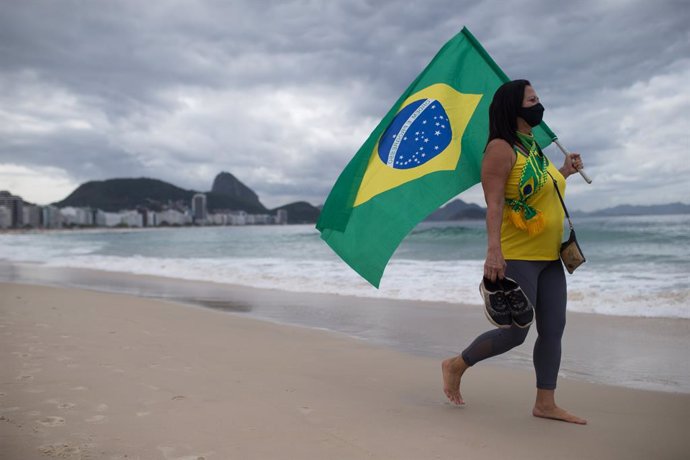 01 May 2021, Brazil, Rio de Janeiro: A supporters of Brazilian President Jair Bolsonaro holds a flag during a protest at Copacabana beach, to mark the May Day, International Worker' Day. Photo: Fernando Souza/dpa