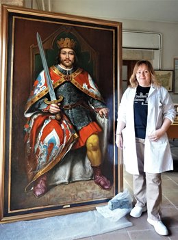 La restauradora Elisa Lobato, profesora del COAO, posa junto al lienzo ya restaurado.
