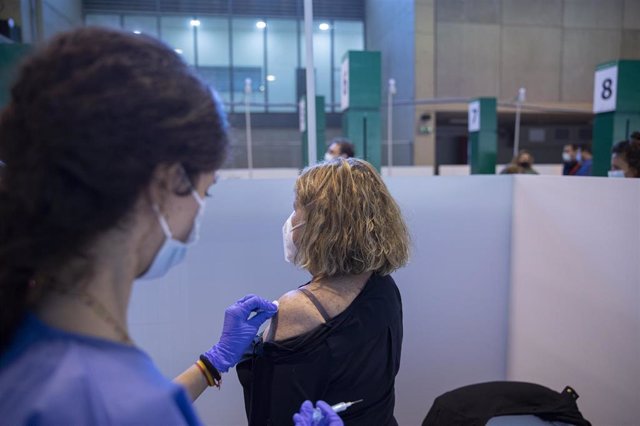 Una sanitaria vacuna a una mujer durante la primera jornada de vacunación ante la Covid-19 en el Estadio de La Cartuja de Sevilla, (Andalucía, España), a 22 de abril de 2021.
