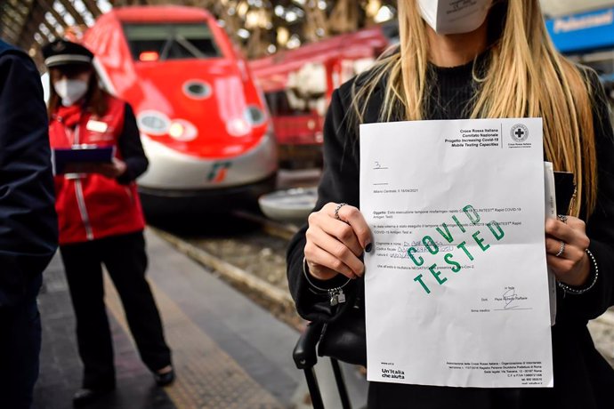 16 April 2021, Italy, Milan: A young woman shows the result of her Corona test at a platform counter in a train station in Milan. Italy's railway company Trenitalia offers so-called "covid-free" connections between Rome and Milan, only for travellers wi