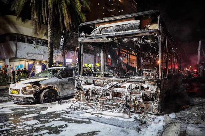 11 May 2021, Israel, Holon: Israeli firefighters work around burnt bus and car, after they were hit by a rocket fired by the Palestinian Islamist movement Hamas from Gaza towards Israel amid the escalating flare-up of Israeli-Palestinian violence. Photo