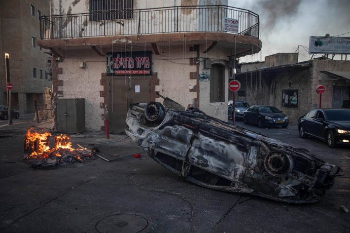 11 May 2021, Israel, Lod: A car is seen burnt during renewed riots in the city of Lod, following the funeral of a 25-year-old Israeli-Arab man who was shot and killed during riots the previous night. Violent clashes continue between police and Israeli A