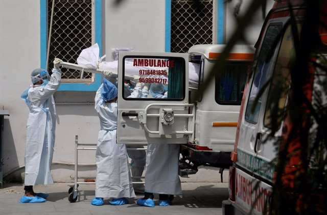 Trabajadores sanitarios de India trasladan un cadáver durante la pandemia de coronavirus