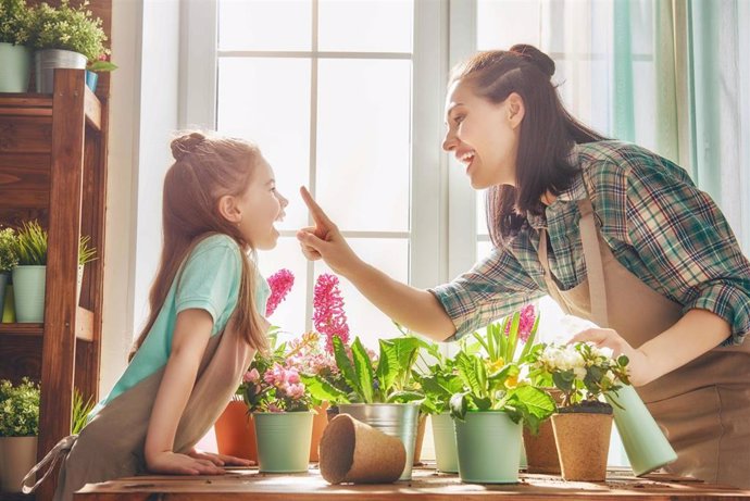 Archivo - Cute child girl helps her mother to care for plants. Mom and her daughter engaged in gardening near window at home. Happy family in spring day.