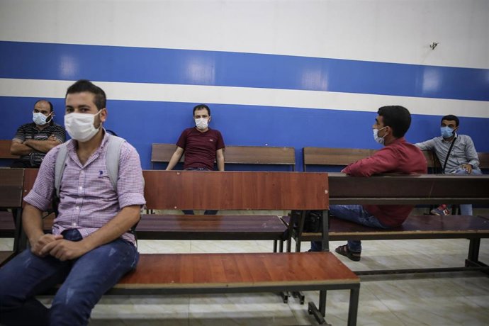 Archivo - Ciudadanos sirios con mascarillas esperando en el paso fronterizo con Turquía en Bab al Hawa