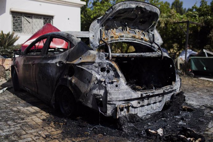 12 May 2021, Israel, Lod: A burnt car is seen in front of a damaged house that was hit last night in Dahmash village near the city of Lod by a rocket fired by the Palestinian Islamist movement Hamas from Gaza towards Israel amid the escalating flare-up 