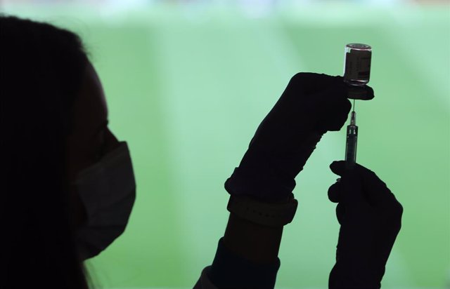 Un profesional sanitaria sostiene una jeringuilla y un vial con la vacuna del Covid-19, en un dispositivo instalado en el Estadio Wanda Metropolitano, en Madrid (España), a 30 de marzo de 2021. La Comunidad de Madrid ha comenzado a vacunar este martes f