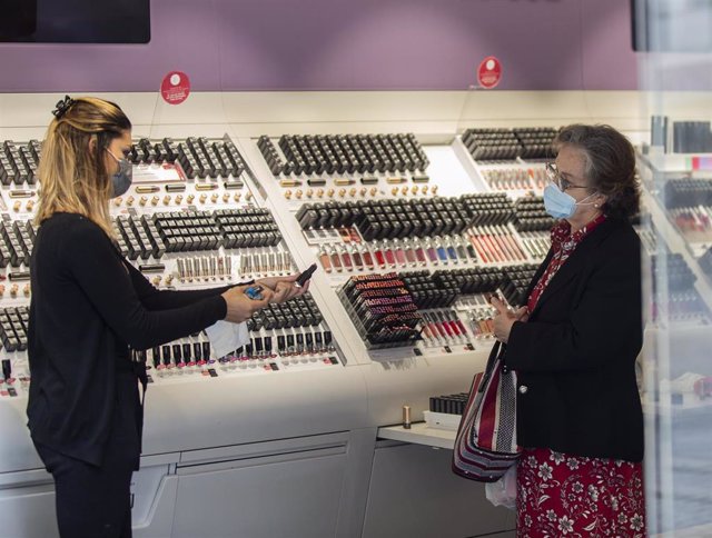 Archivo - Una empleada de una tienda de cosmética atiende a una clienta  durante el segundo día de la fase 1 del plan de desescalada que ha elaborado el Gobierno de España. En Sevilla, (Andalucía, España), a 12 de mayo de 2020. (Foto de archivo).