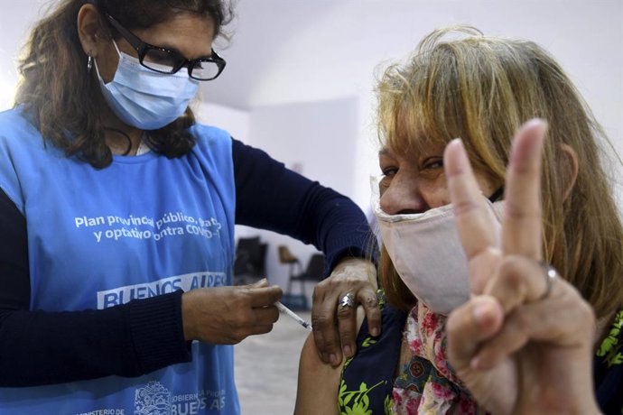 20 April 2021, Argentina, Buenos Aires: A woman makes the victory sign while receiving a Covid-19 vaccine in Buenos Aires province. Photo: ---/telam/dpa