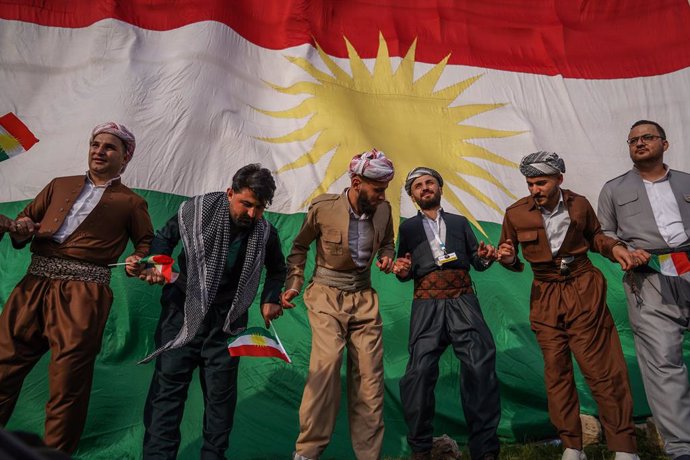Archivo - 20 March 2021, Iraq, Akre: Kurdish men dance, backdropped by a giant Kurdish flag, during the celebrations of Nowruz, the Persian new year. The Persian New Year or the Kurdish New Year is an old Zoroastrian tradition celebrated by Iranians and