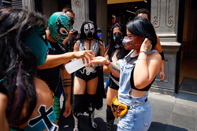 luchadores mexicanos distribuyen gel antibacteriano a las personas durante un evento en las calles de Ciudad de México.