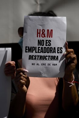 Una persona sostiene un folio donde se puede leer "H&M no es empleadora, es destructura" durante una concentración 
