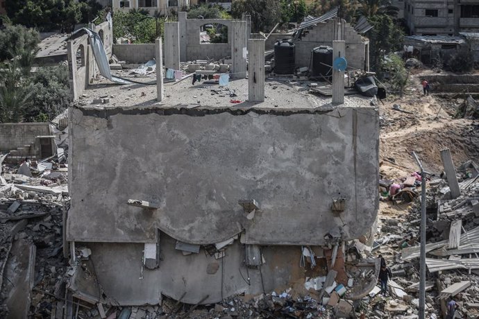 13 May 2021, Palestinian Territories, Beit Lahia: People inspect a destroyed building on the northern Gaza Strip town of Beit Lahia after it was hit by an Israeli airstrike early in the morning, amid the escalating flare-up of Israeli-Palestinian violen