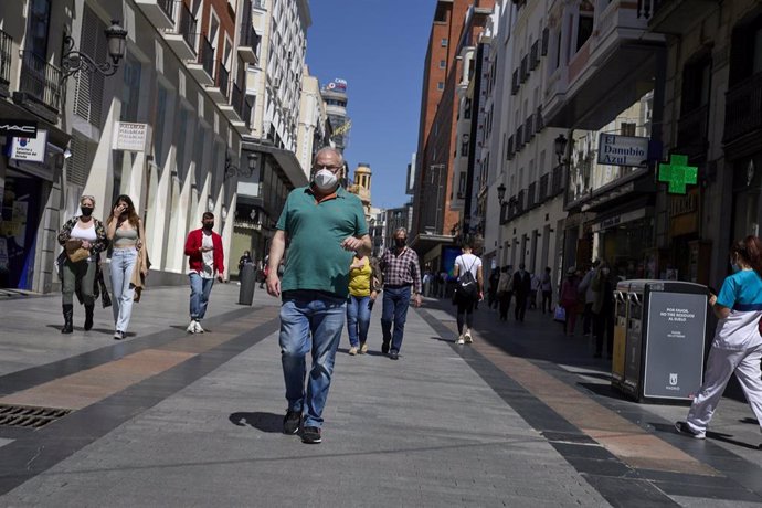 Varias personas pasean por una calle céntrica de una ciudad. 