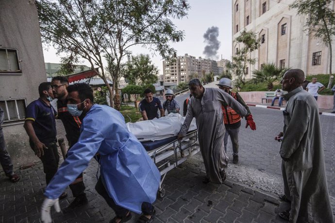 13 May 2021, Palestinian Territories, Gaza City: Relatives and Palestinian medics transport the body of a Palestinian who killed after an Israeli airstrike on Gaza City amid the escalating flare-up of Israeli-Palestinian violence. The Ministry of Health