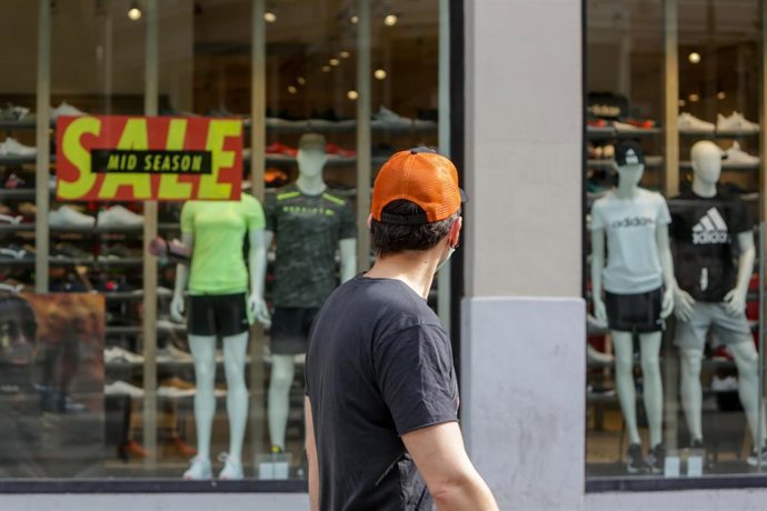 Archivo - Un hombre mira el escaparate de una tienda.
