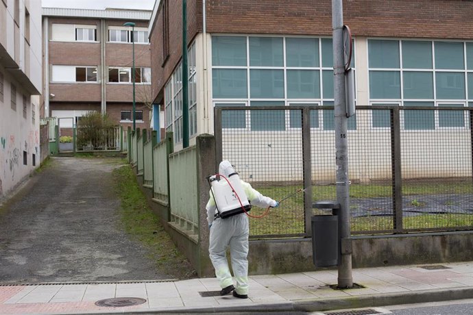 Archivo - Una persona desinfecta el perímetro que rodea el colegio público CEIP  Paradai, en Lugo, Galicia (España), a 19 de febrero de 2021. Sanidad de Lugo confirmó ayer que ascienden a 60 los positivos de un brote vinculado al colegio Paradai de Lugo