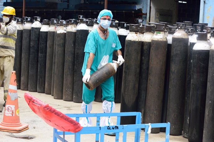 13 May 2021, India, Kolkata: A worker wearing a face mask unloads an empty oxygen cylinder for refilling at a hospital in Kolkata as Coronavirus (Covid-19) positive cases and deaths surge in India. Photo: Sumit Sanyal/SOPA Images via ZUMA Wire/dpa