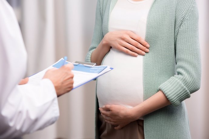 Archivo - Cropped shot of doctor writing down while pregnant woman holding stomach