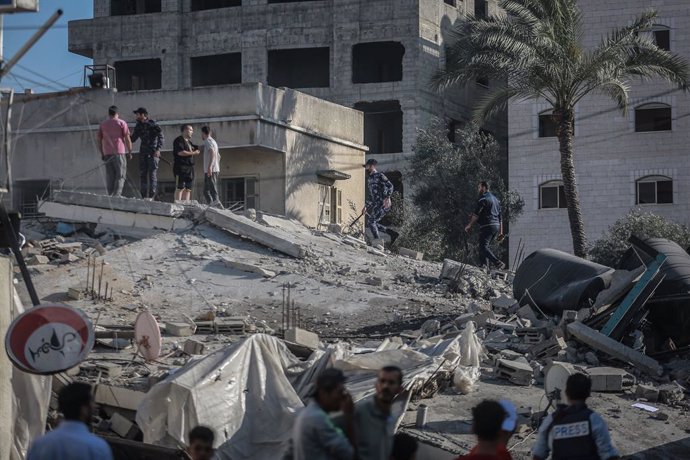 14 May 2021, Palestinian Territories, Gaza City: Palestinians inspect the remains of the "Production Bank", an institution linked to the Palestinian Islamist movement Hamas, after it was hit by Israeli airstrikes, amid the escalating flare-up of Israeli