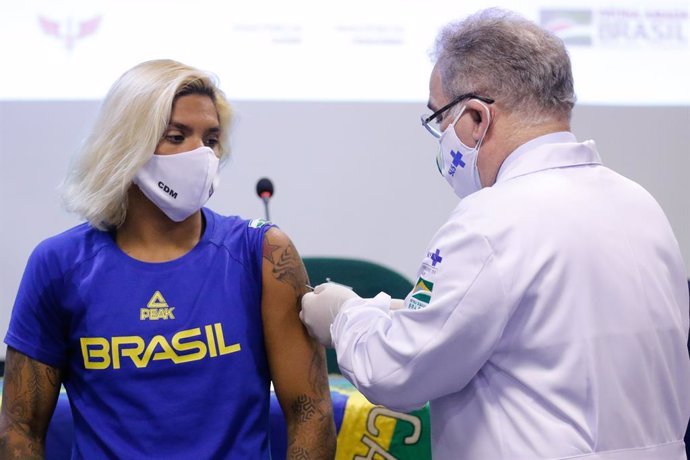 14 May 2021, Brazil, Rio De Janeiro: Brazil's Minister of Health Marcelo Queiroga (R), administers a Corona vaccination to swimmer Ana Marcela Cunha (L), who is scheduled to compete in the Tokyo Olympics this year. Photo: Fernando Frazo/Agncia Brasil/