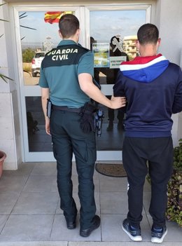 Un agente de la Guardia Civil con el detenido como presunto autor de hasta cinco robos en comercios e interior de vehículos en Felanitx.