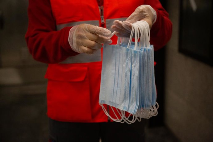 Archivo - Arxiu - Una voluntria de Creu Roja es prepara per donar mascaretes a l'estació catalana de Diagonal el dia en qu es reactiva l'activitat laboral no essencial a Catalunya