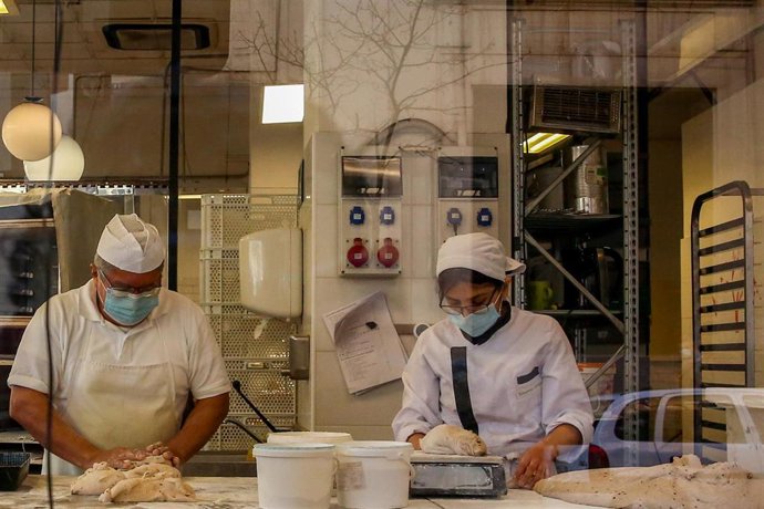Archivo - Dos reposteros colocan varios roscones de reyes en la panadería La Magdalena de Proust, en Madrid (España)