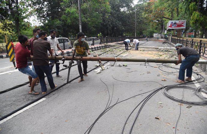16 May 2021, India, Guwahati: Workers remove the electric pillars from a road after the Tropical storm Tauktae hit India's western coast. Photo: Dasarath Deka/ZUMA Wire/dpa