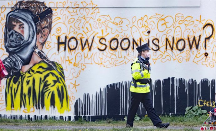 18 April 2021, United Kingdom, Dublin: A police officer walks past a new mural at Dublin's Grand Canal Docks by the artist CHELS (Chelsea Jacobs), reflecting the uncertain future of children due to Covid-19 restrictions. Photo: Niall Carson/PA Wire/dpa