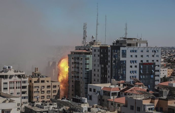 15 May 2021, Palestinian Territories, Gaza City: Smoke and flames rise after an Israeli air-strike hits at Al-Jalaa tower, which houses apartments and several media outlets, including The Associated Press and Al Jazeera, amid the escalating flare-up of 
