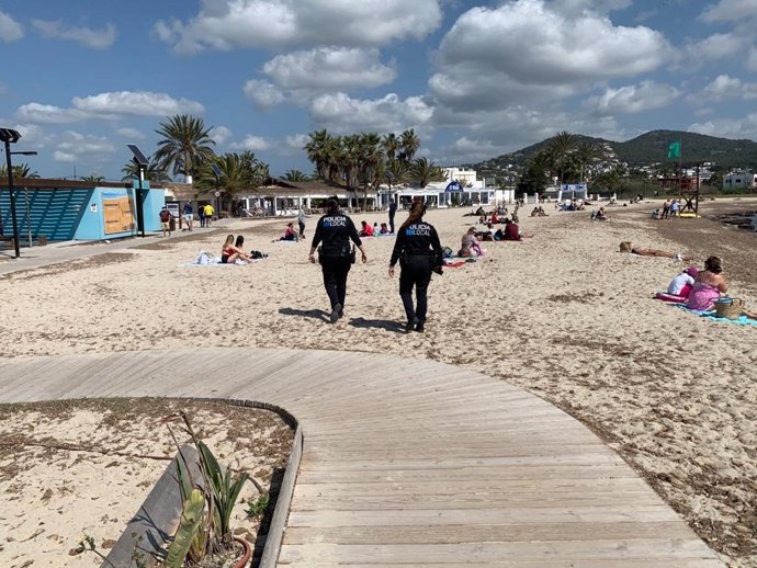 Archivo - Agente de policía y bañistas en una playa de Ibiza.