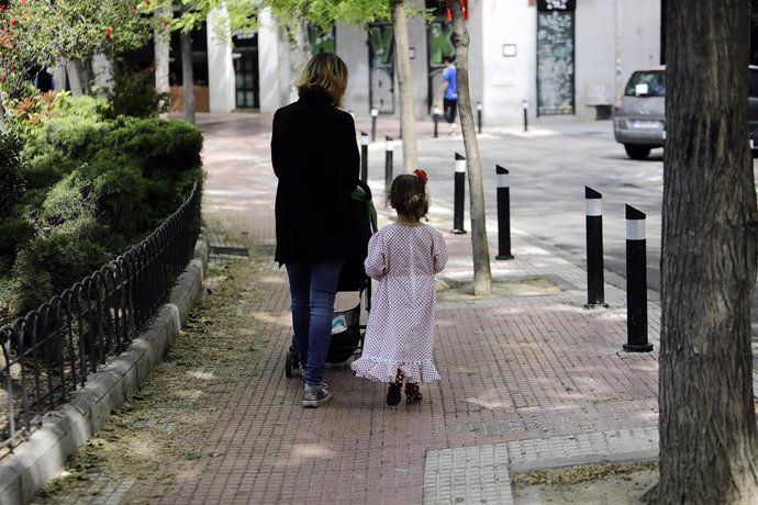 Archivo - Una mujer camina con su hija vestida de chulapa por el centro de la capital.