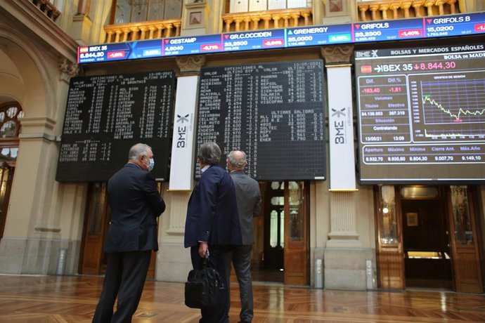Tres hombres observan valores económicos en el Palacio de la Bolsa, a 13 de mayo de 2021, en Madrid (España). El Ibex 35 cedía un 1,94% en la media sesión de este jueves, alejándose de los 8.900 puntos, arrastrado por las caídas registradas ayer en Wall