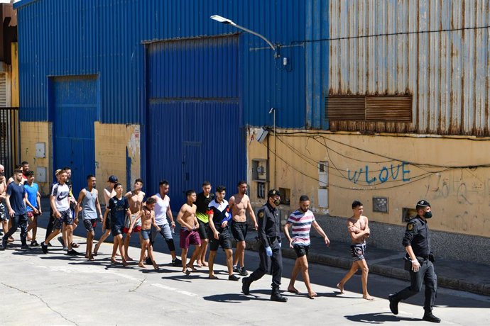 Un grupo de jóvenes migrantes marroquíes en fila en las inmediaciones de una nave, a 17 de mayo de 2021, en Ceuta (España). La delegación ha cifrado que unas 1000 personas, de las que al menos 300 son menores de edad, han conseguido sortear los espigone