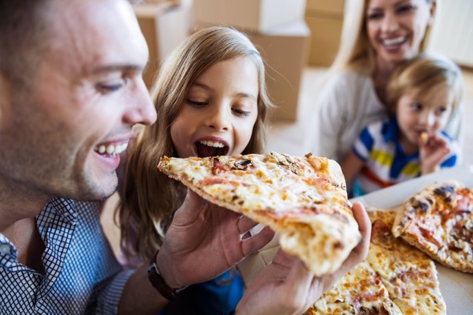 Archivo - Familia feliz comiendo pizza