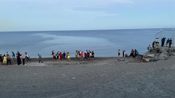 Personas migrantes caminan por la playa del Tarajal, a 17 de mayo de 2021, en Ceuta (España).