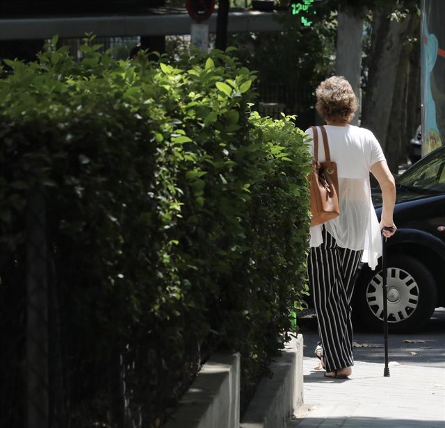 Archivo - Una mujer de la tercera edad pasea con un bastón por una calle de Madrid.