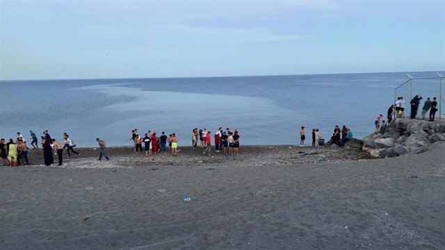 Personas migrantes caminan por la playa del Tarajal para acceder a Ceuta de forma irregular