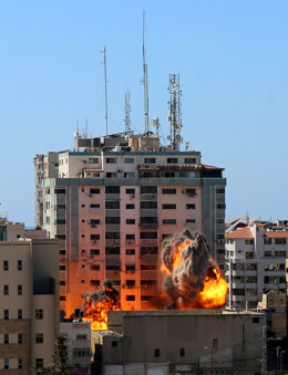 15 May 2021, Palestinian Territories, Gaza City: Smoke and flames rise after an Israeli air-strike hits at Al-Jalaa tower, which houses apartments and several media outlets, including The Associated Press and Al Jazeera, amid the escalating flare-up of 