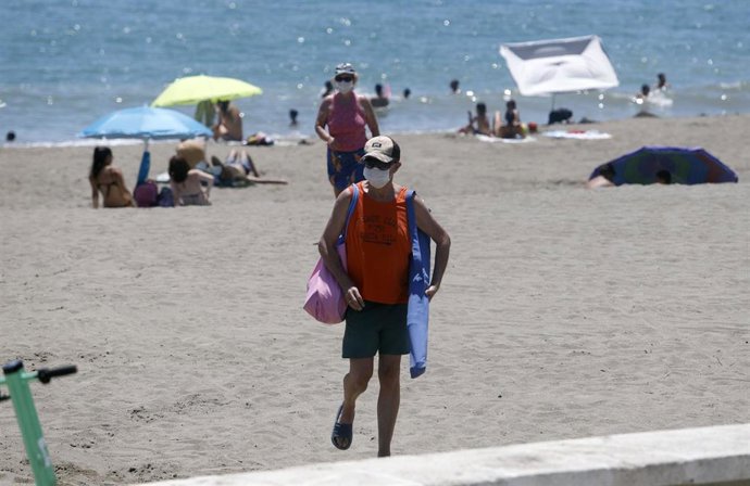 Archivo - Personas con mascarilla saliendo de una playa de Málaga