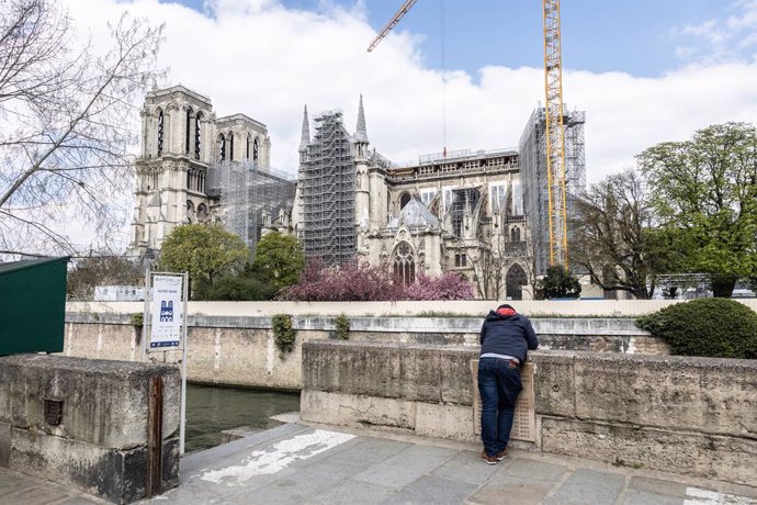 Archivo - 08 April 2021, France, Paris: A man stands on the bank of the Seine River, opposite to the Notre-Dame de Paris Cathedral, almost two years since restoration work began to renovate the architectural marvel following the fire of 15 April 2019. P