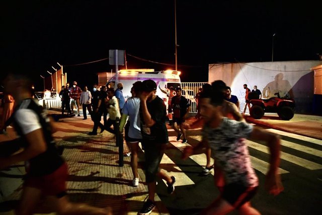 Personas migrantes corren tras su llegada a la playa del Tarajal, a 17 de mayo de 2021, en Ceuta (España). España ha movilizado al Ejército en la ciudad tras la entrada de más de 5.000 marroquíes en 24 horas.