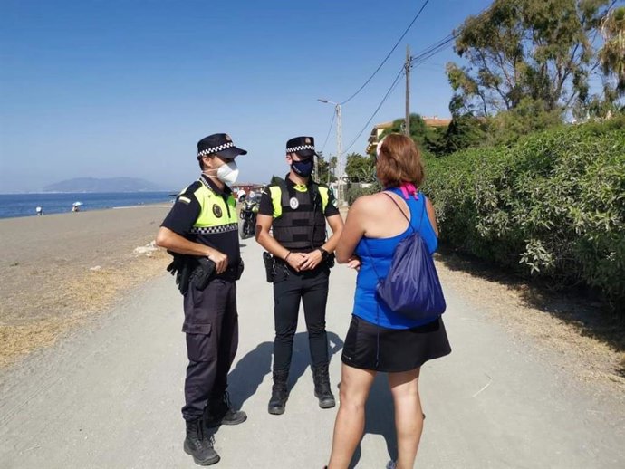 Dos agentes de policía de Rincón de la Victoria dialogan con una ciudadana