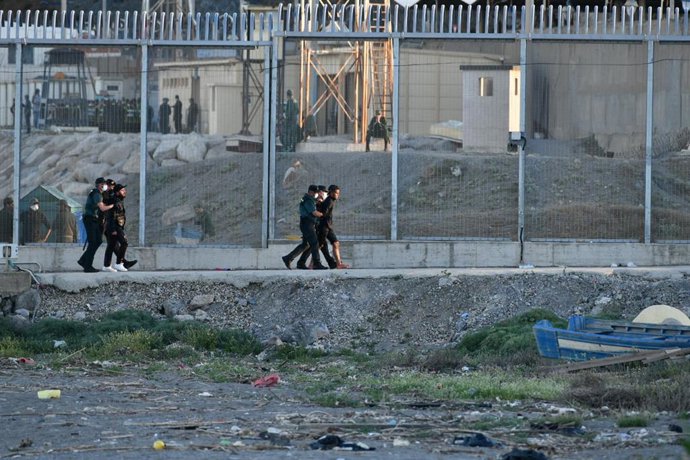 Agentes de Policía y personas migrantes en la playa del Tarajal, a 17 de mayo de 2021, en Ceuta (España). España ha movilizado al Ejército en la ciudad tras la entrada de más de 5.000 marroquíes en 24 horas.