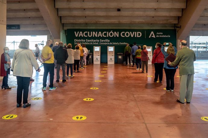 Varias personas esperan su turno  para recibir la vacuna contra el Covid-19, a 28 de abril de 2021, en el Estadio de la Cartuja, en Sevilla, (España)